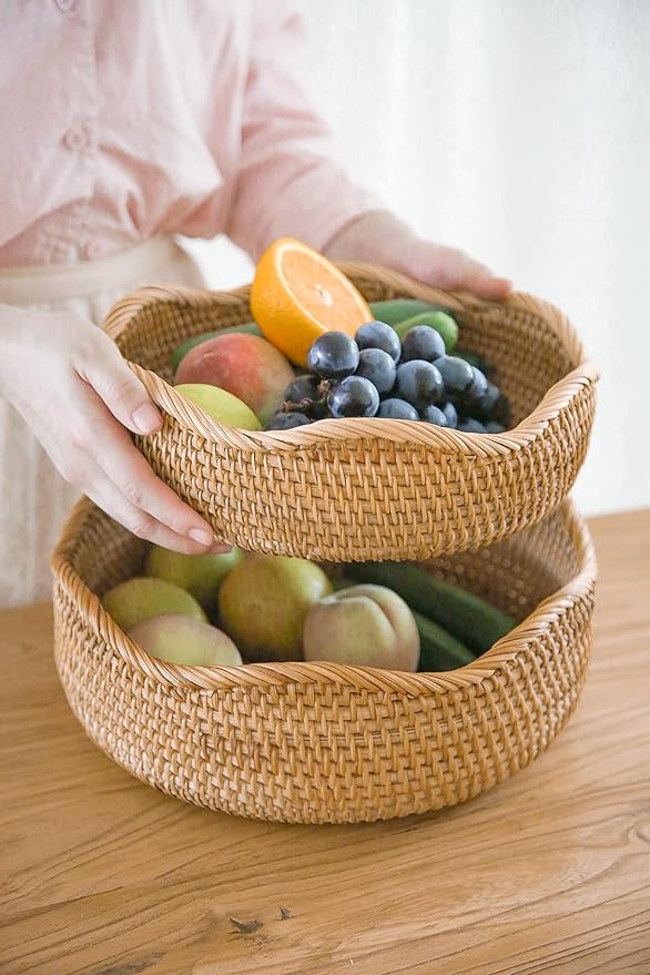 A woman holding two baskets organizers filled with various fruits.