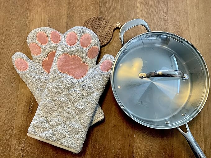 A pair of oven mitts and a pan on a wooden table.