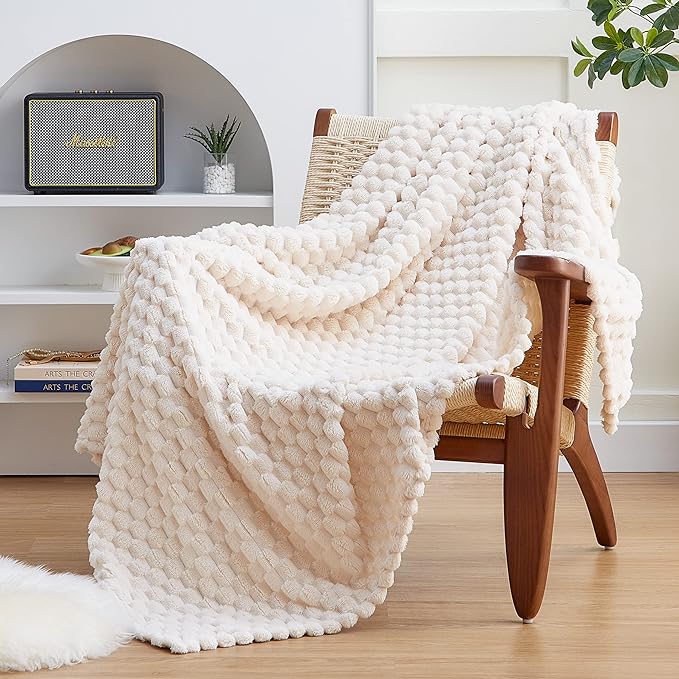 A white throw blanket on a chair in a living room.