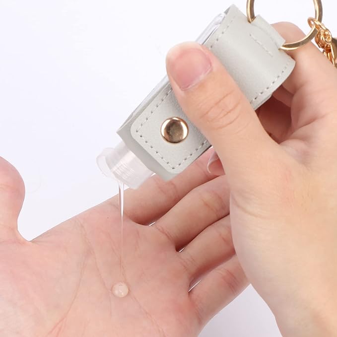 A person holding a key chain with a small bottle of hand sanitizer.