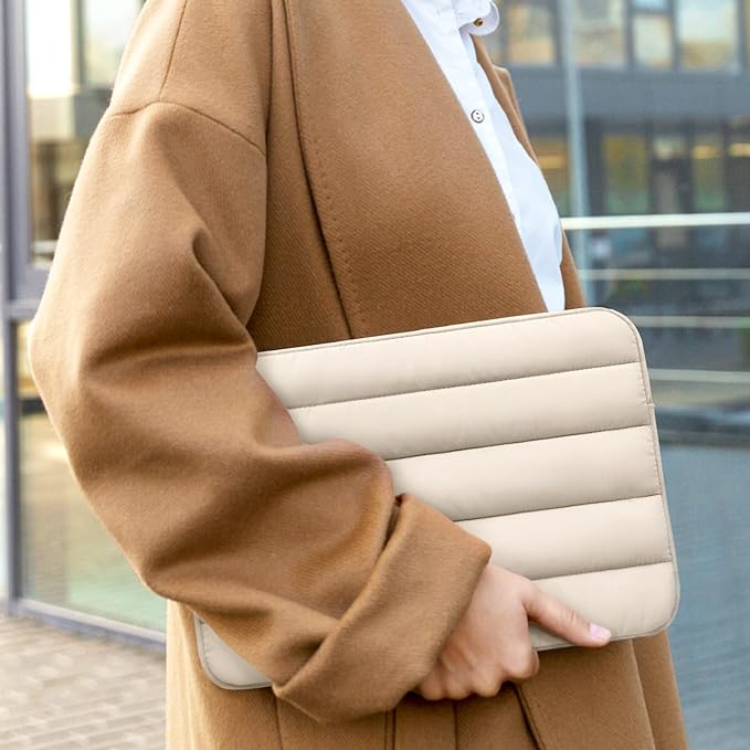 Woman in coat holding a laptop in beige laptop sleeve