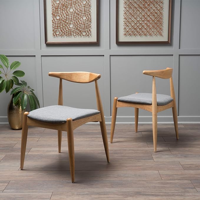 Two oak finish chairs with upholstered seats in grey placed next to a plant in a vase