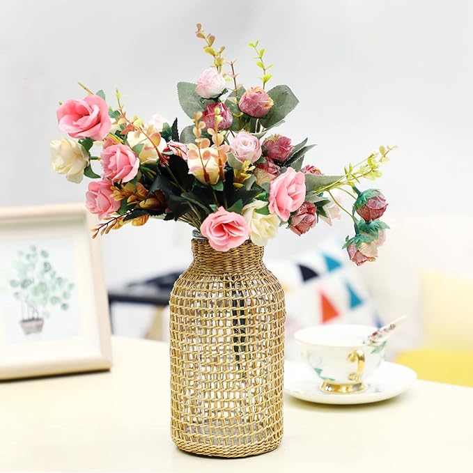 A rattan covered vase filled with pink and white flowers placed on a table.