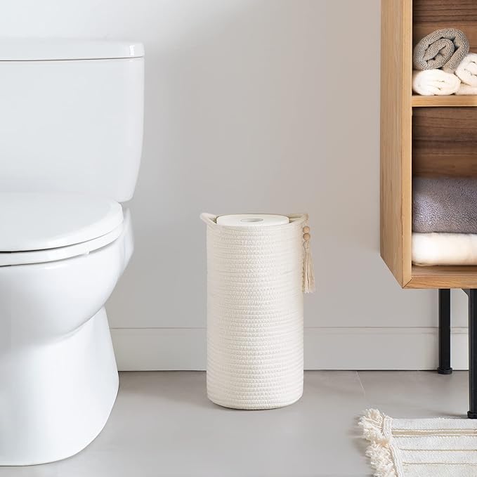 A cotton toilet paper holder in a bathroom with toilet and cabinet.